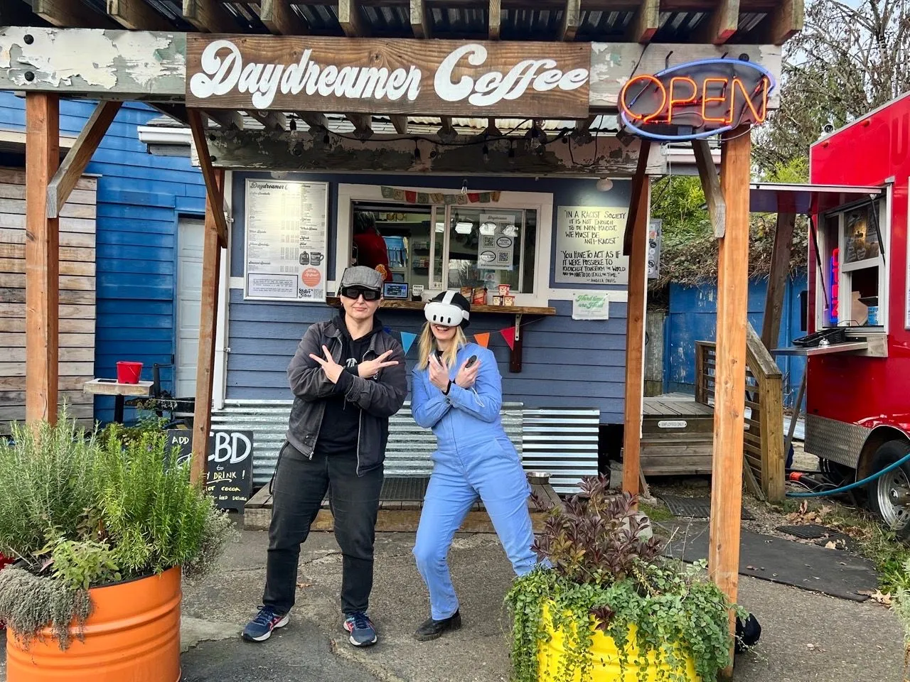 Daydreamer Coffee’s walk-up window: two people in front of the blue building, one in a VR headset, under the hand-painted sign